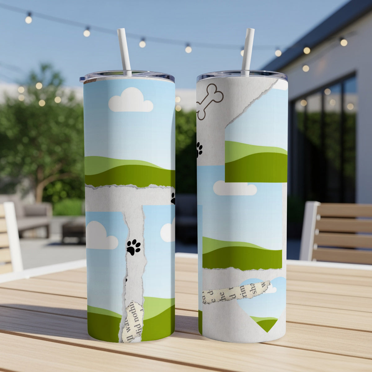 Two tumblers with sky, clouds, grassy hills, paw prints, and torn paper designs.