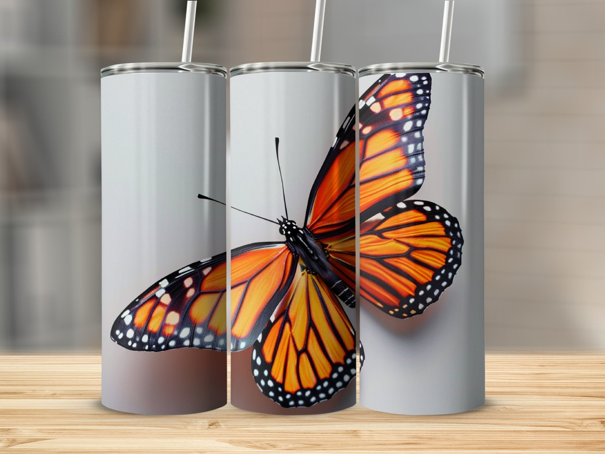 Monarch butterfly on three blank tumblers with straws.