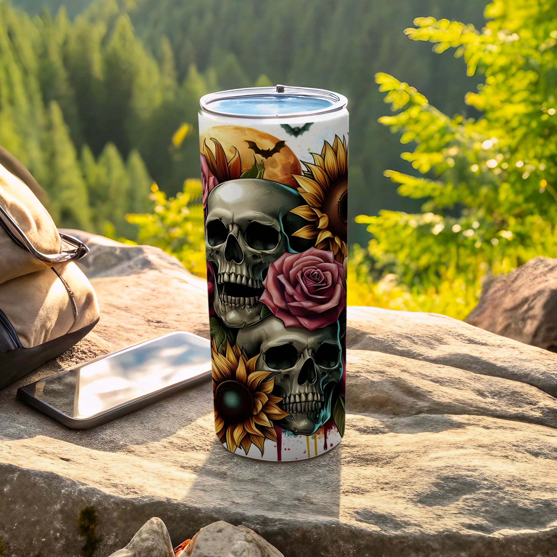 Skulls, roses, and sunflowers wrap around a tumbler, with a backpack and phone nearby.