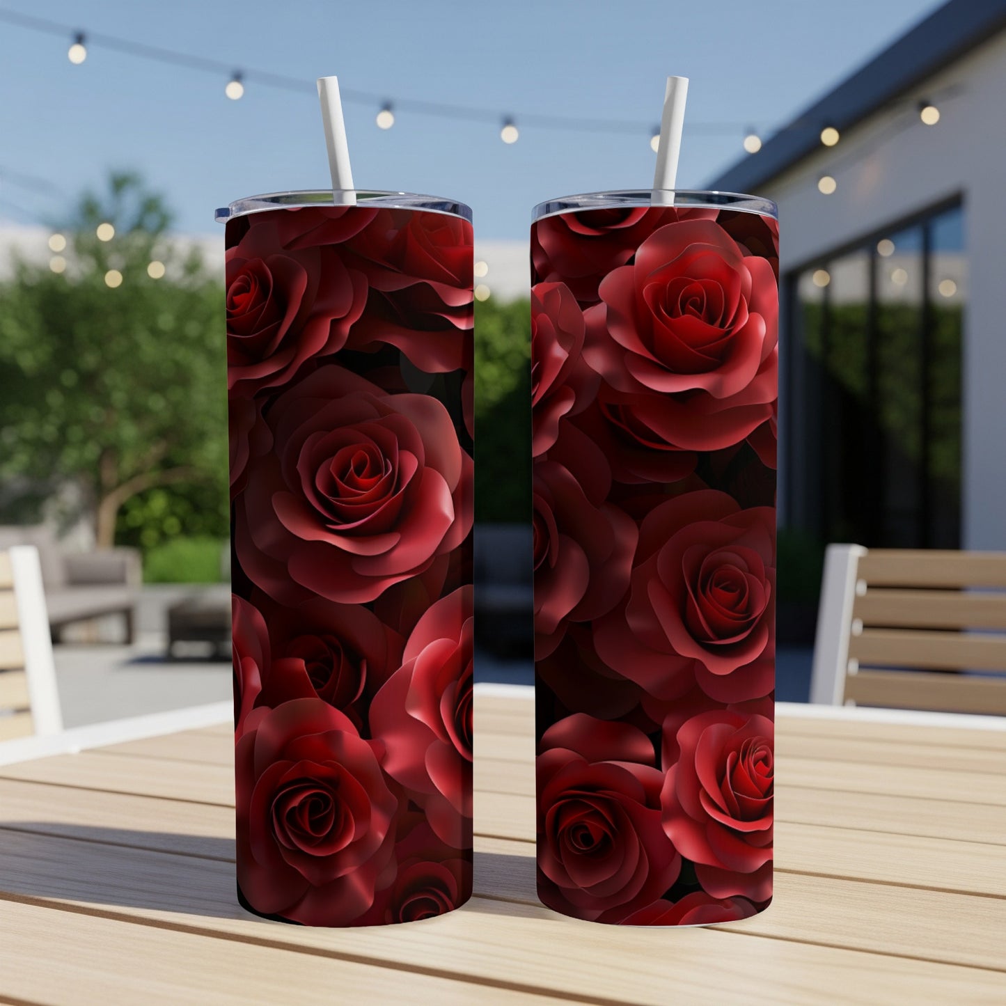 Two dark red rose-patterned tumblers with straws on a wooden table.
