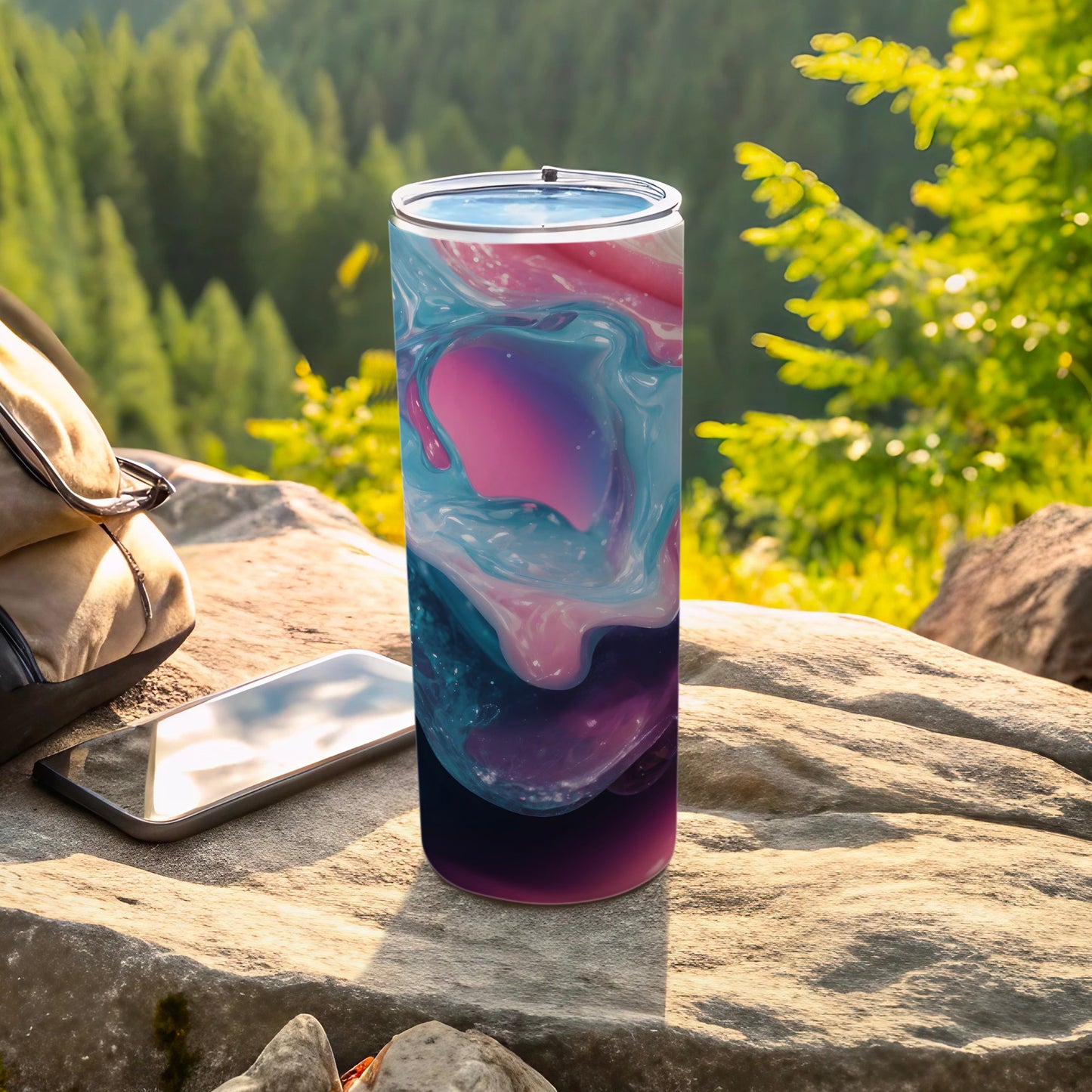 Tumbler with abstract pink, blue, and purple swirl design on rock outdoors.
