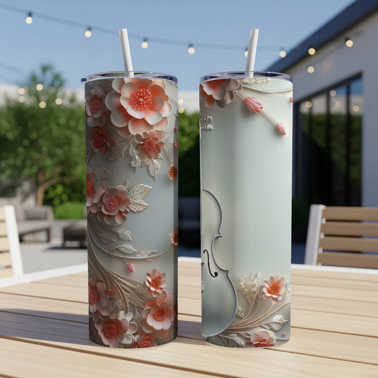 Two tall tumblers with floral and violin designs, standing on a table outdoors.