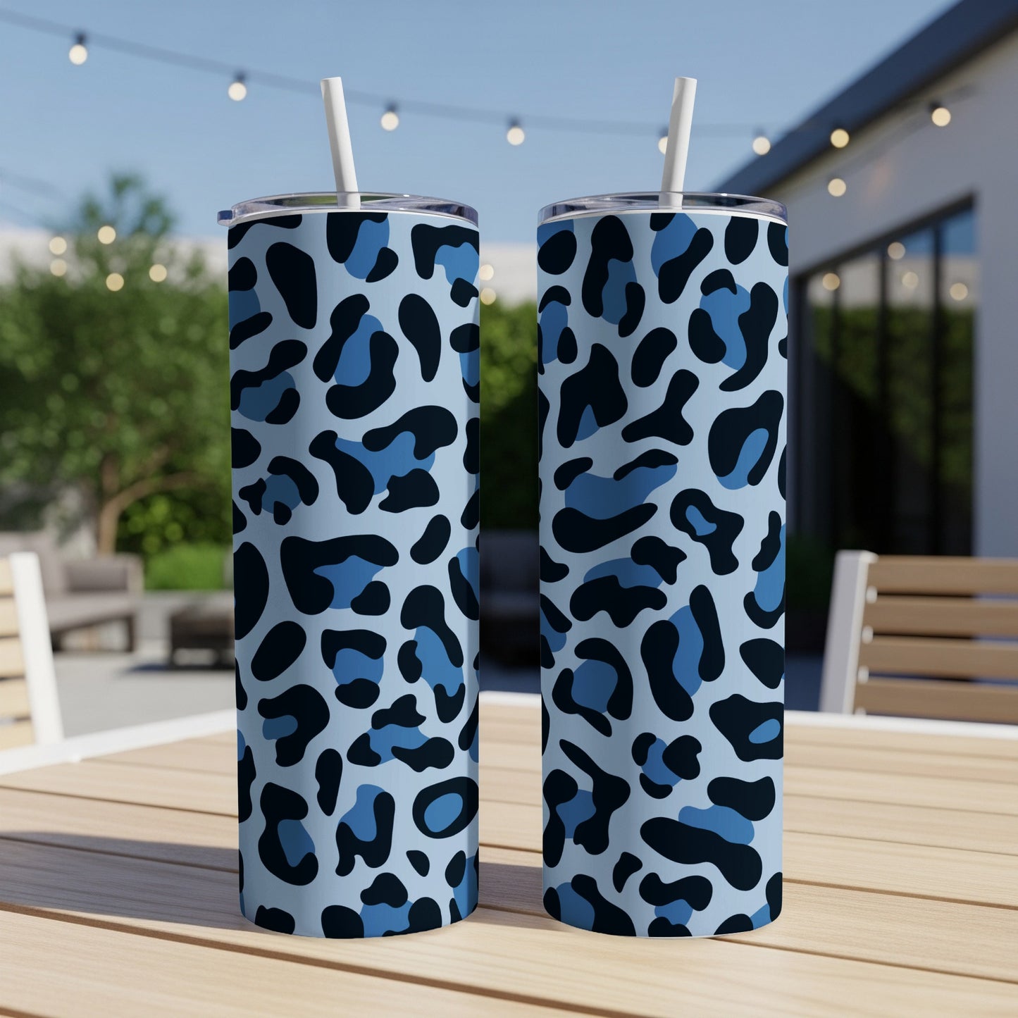 Two blue leopard print tumblers with straws on a wooden table.