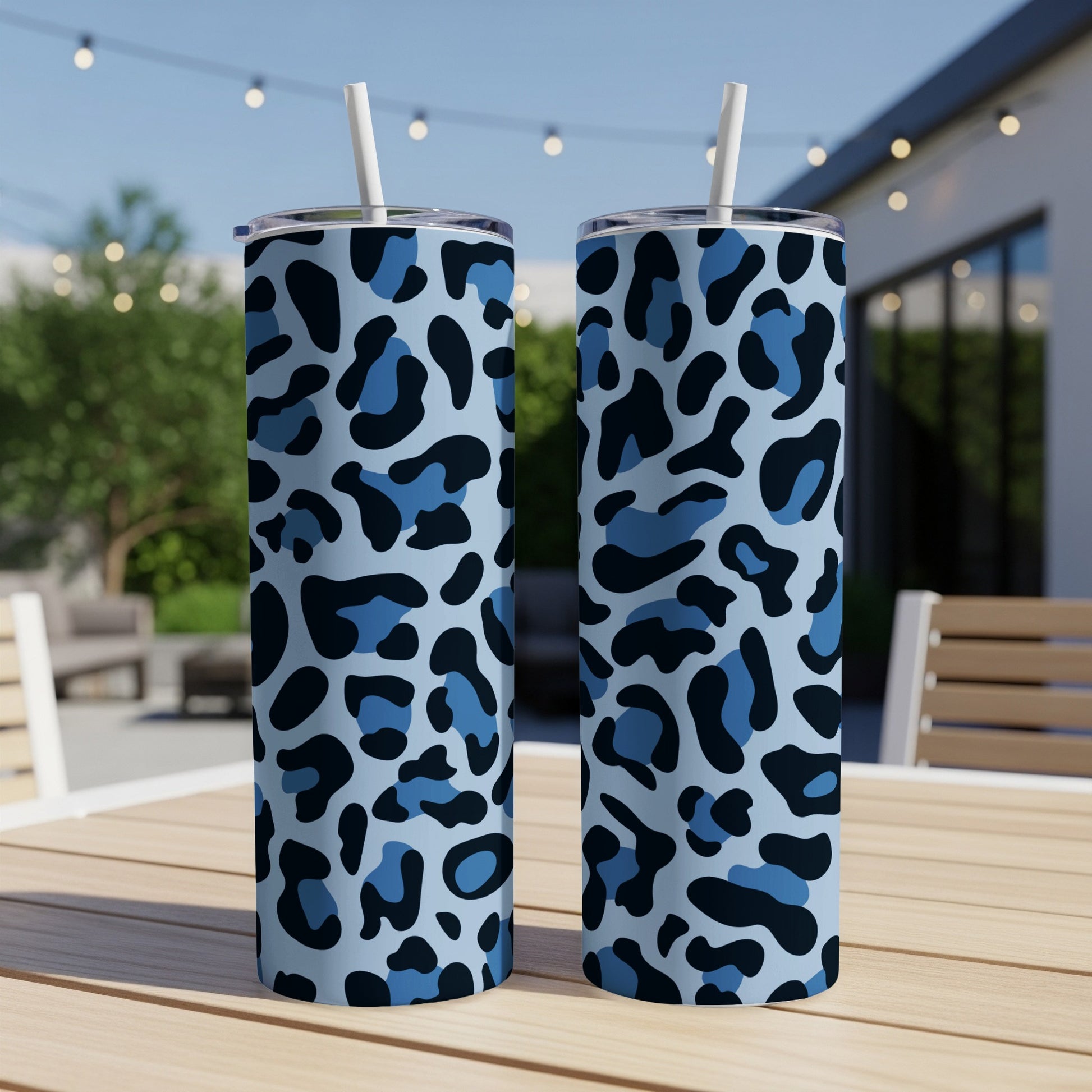 Two blue leopard print tumblers with straws on a wooden table.
