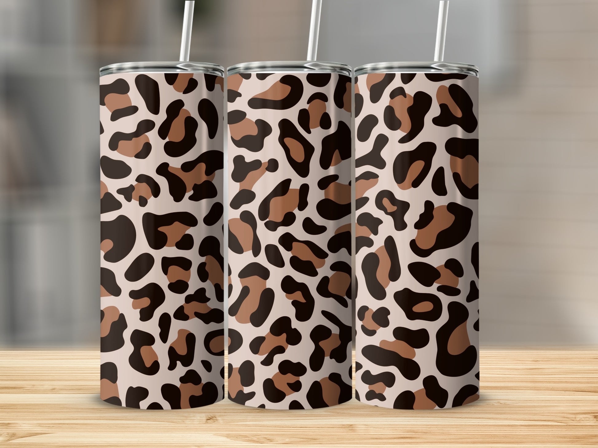 Three tumblers with a leopard print pattern stand on a wooden surface.