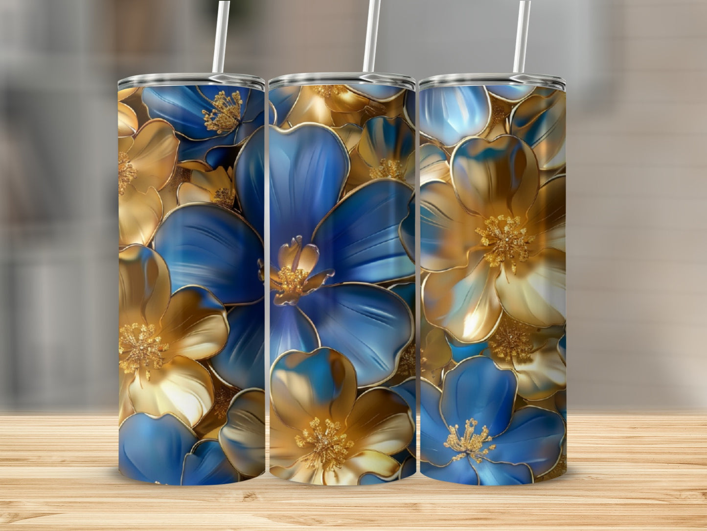 Three tumblers with a gold and blue floral pattern on a wooden surface.