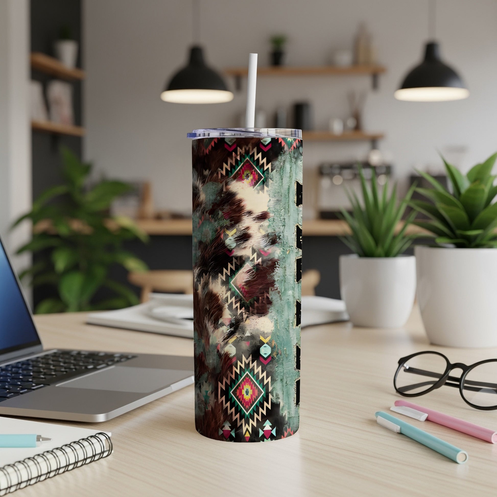 Western-patterned tumbler with straw on a desk next to a laptop.