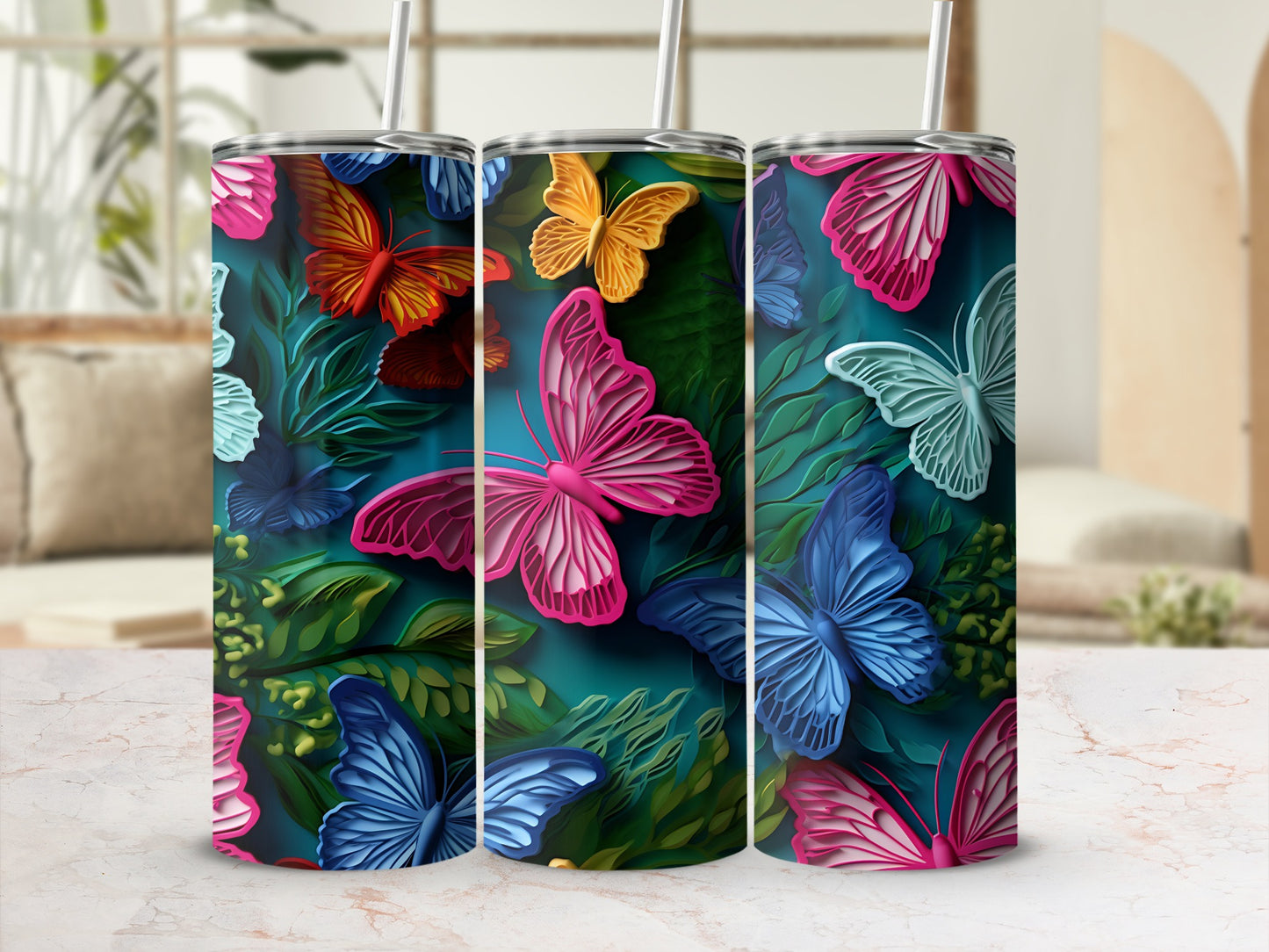 Three tumblers with colorful butterfly and leaf patterns on a marble surface.