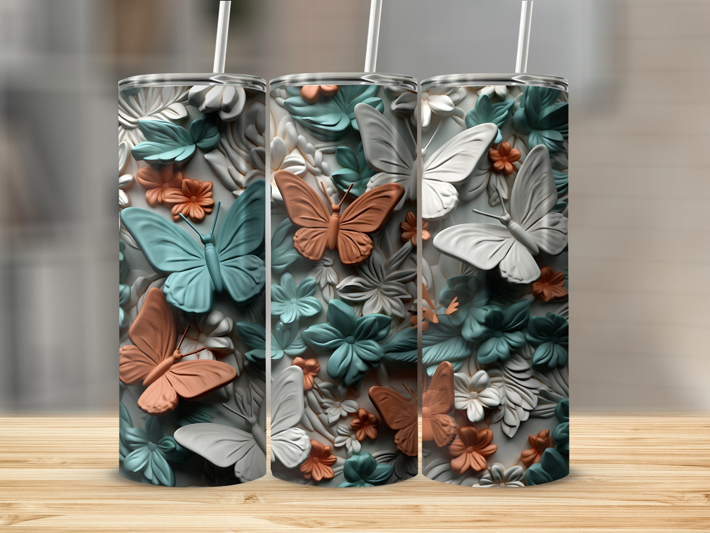 Three floral patterned tumblers with butterflies on a wooden surface.