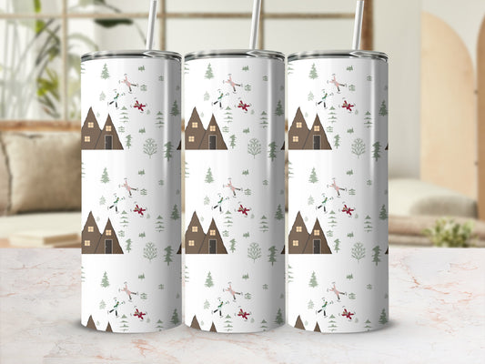 Three tumblers with a snowy cabin and tree design, one with a straw.