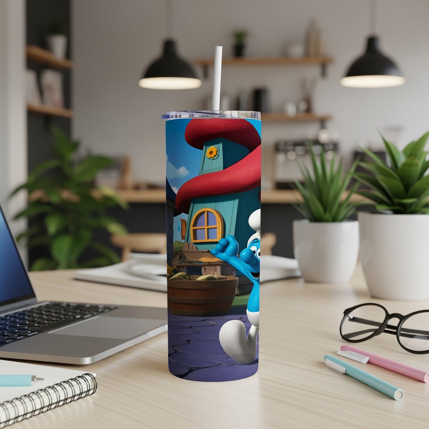Smurf character on a blue tumbler with a straw, sitting on a desk.