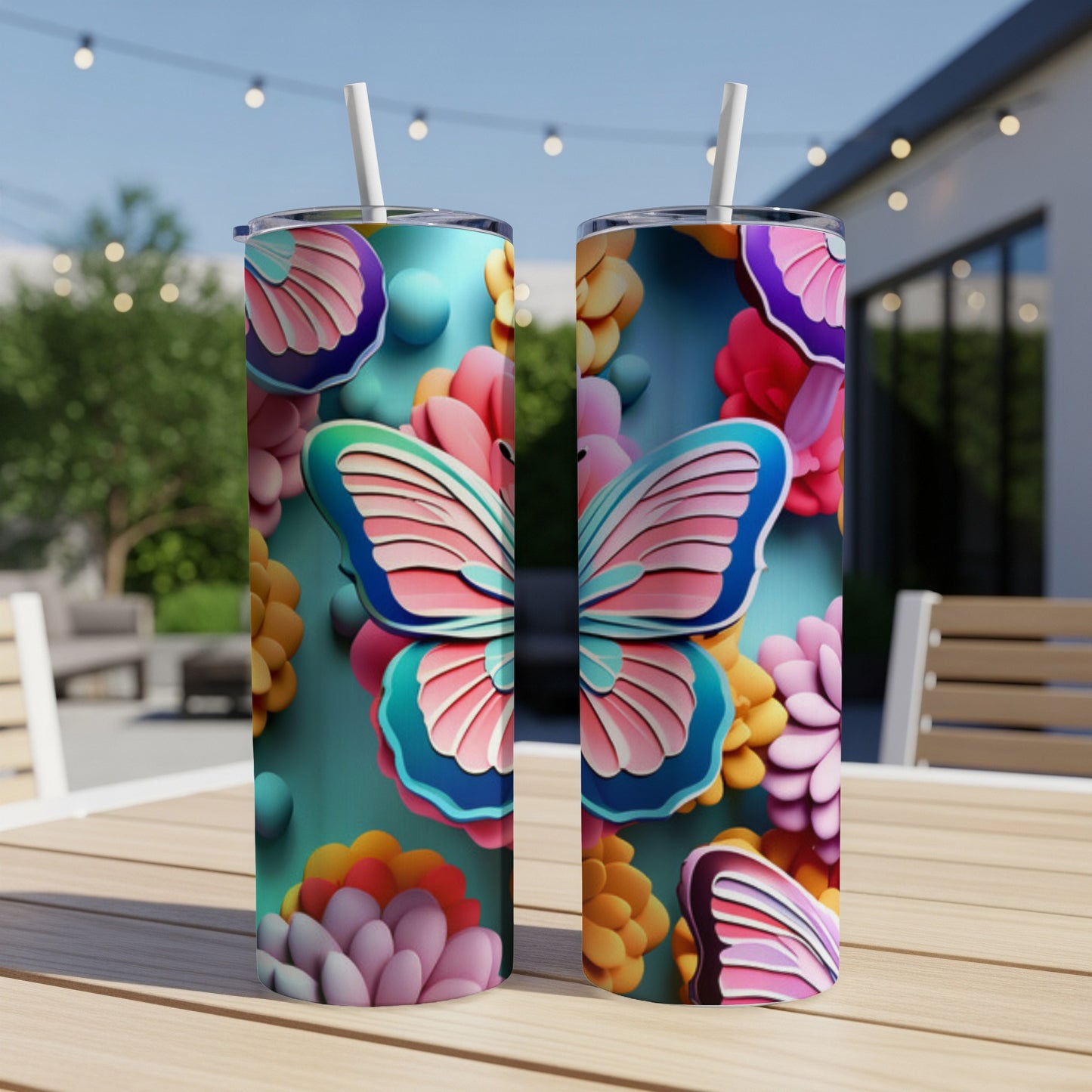 Two skinny tumblers with colorful butterfly and floral designs on an outdoor table.