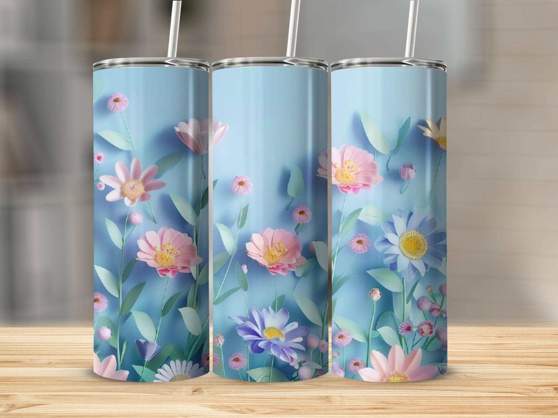 Three light blue tumblers with pastel floral patterns and straws.