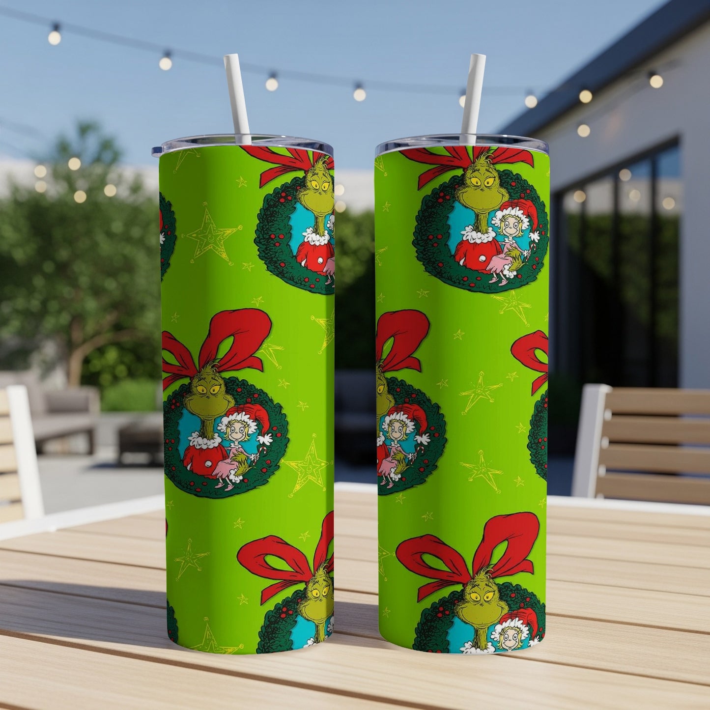 Two green tumblers with Grinch Christmas wreath pattern and red bow.