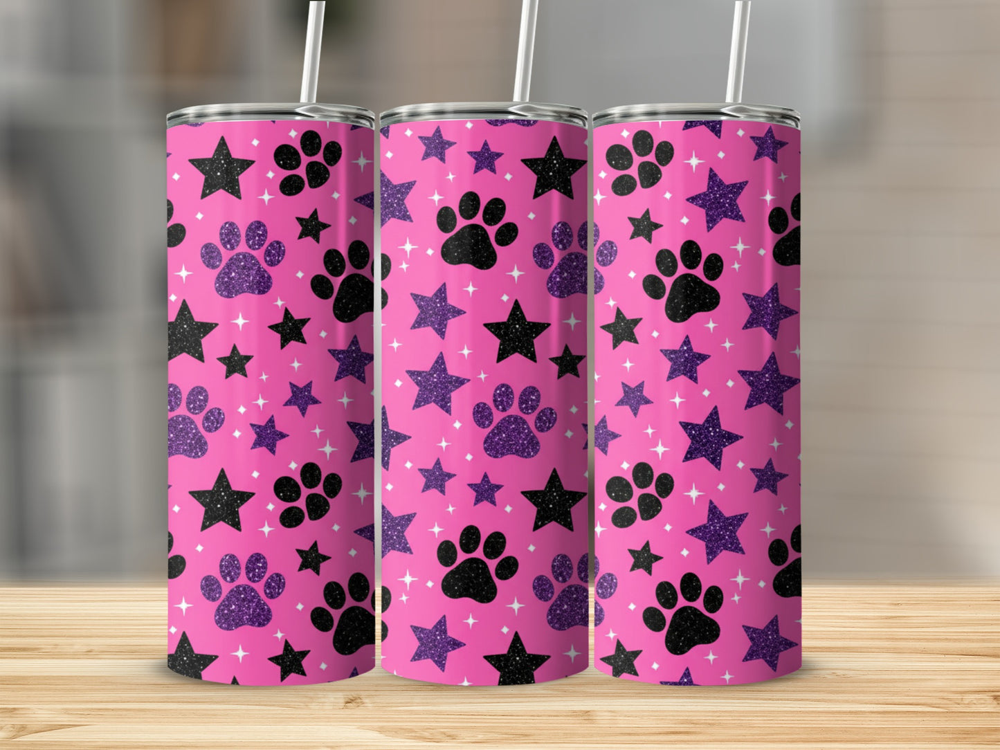 Three pink tumblers with paw prints and stars, on a wooden surface.