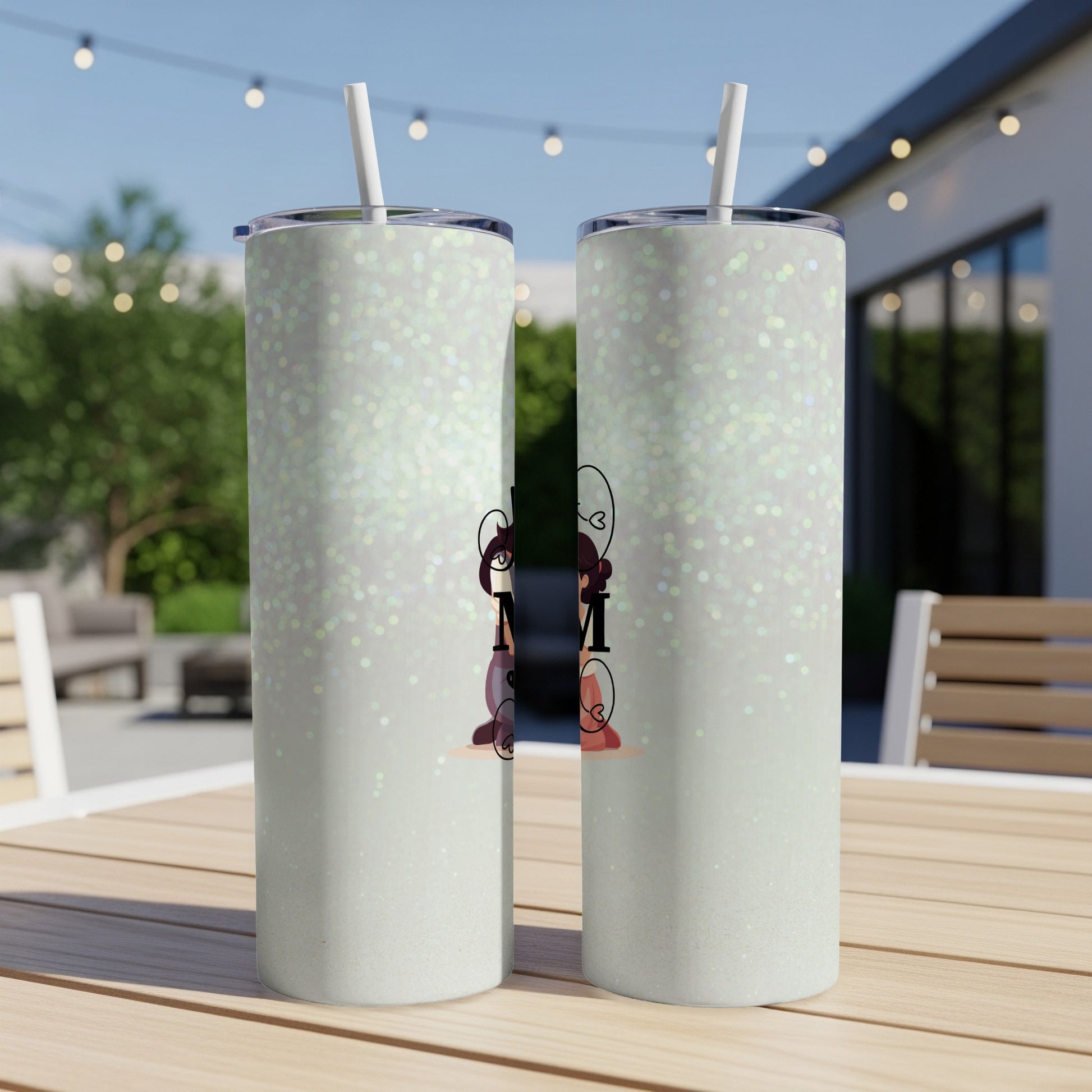 Two glittery tumblers with "Mom" text and floral accents on a table.