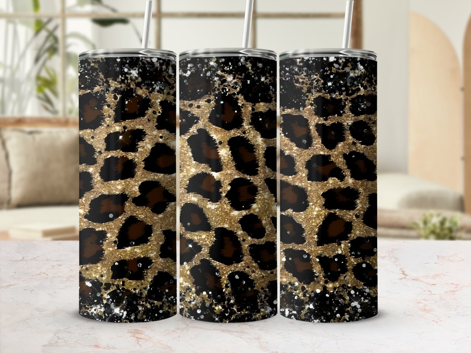 Three glittery leopard print tumblers with straws on a marble surface.