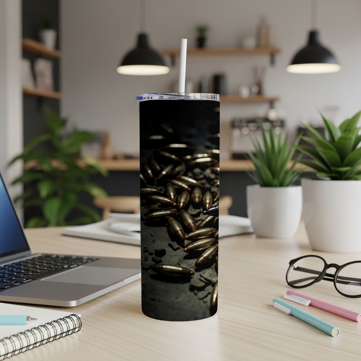 Tumbler with bullets graphic and white straw on a desk with laptop and supplies.