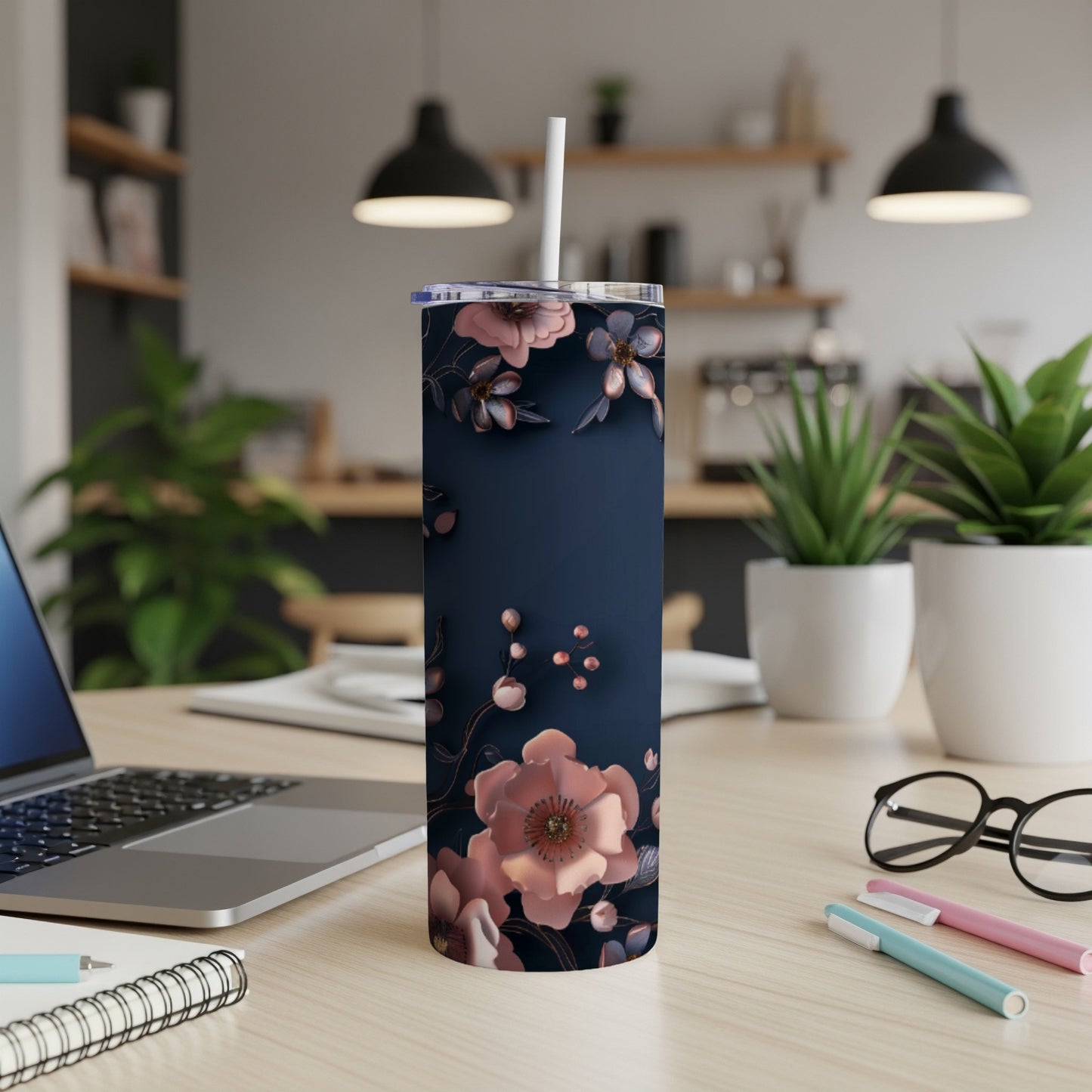 Dark blue tumbler with rose gold floral design on a desk.