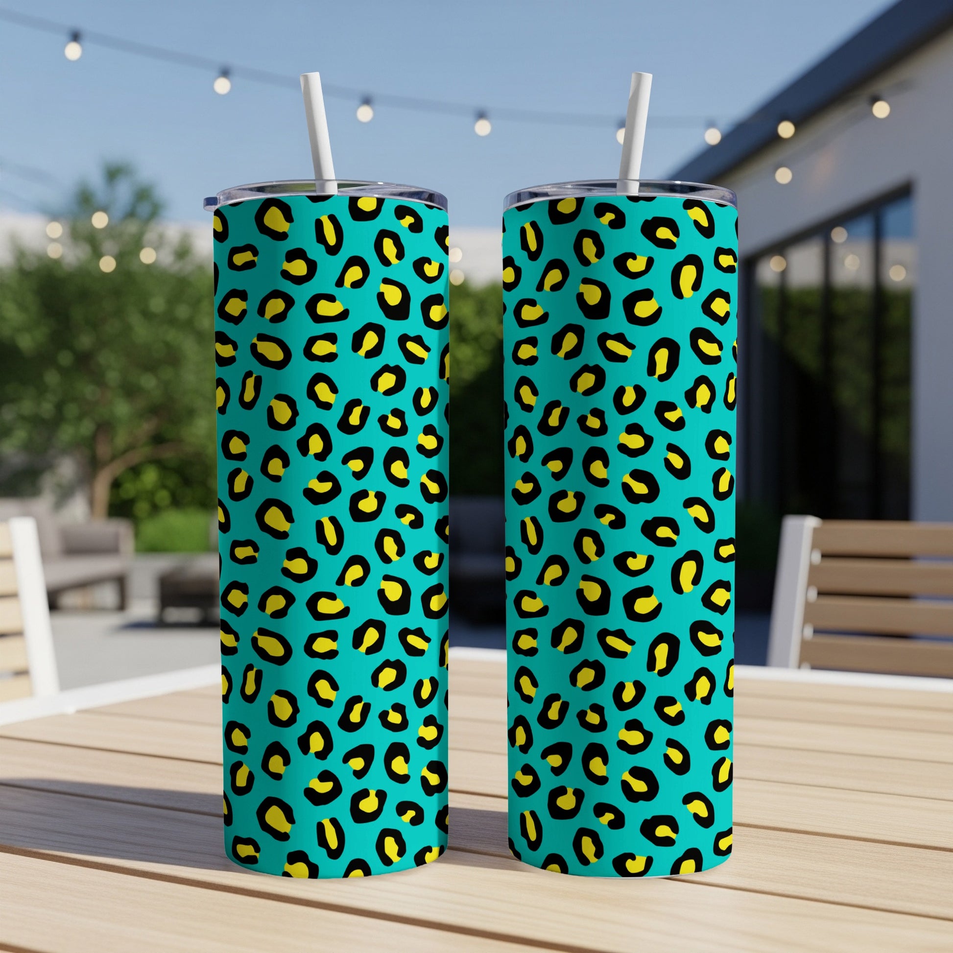 Two teal tumblers with yellow and black leopard print and white straws.