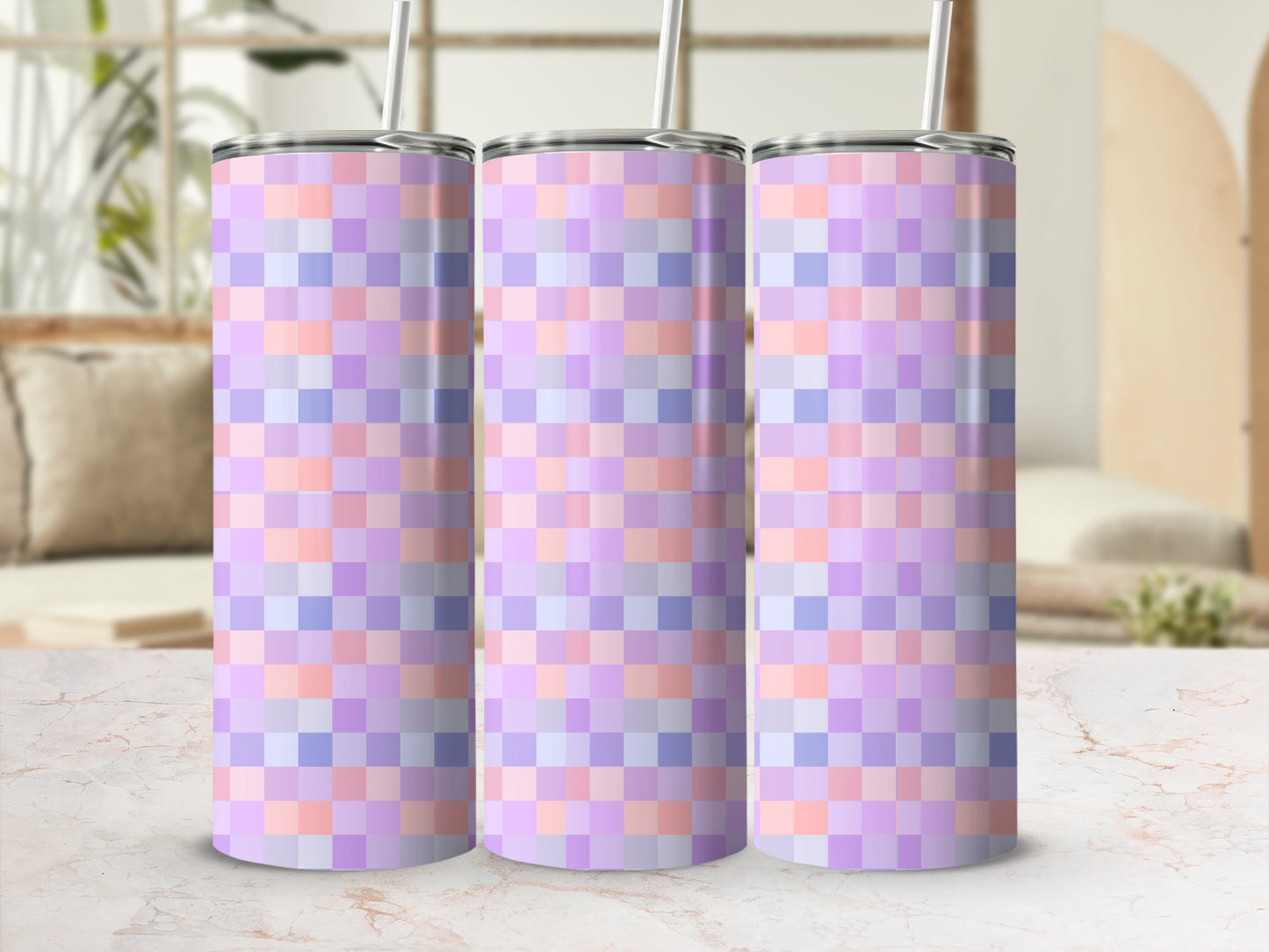Three pastel plaid tumblers with straws on a marble surface.
