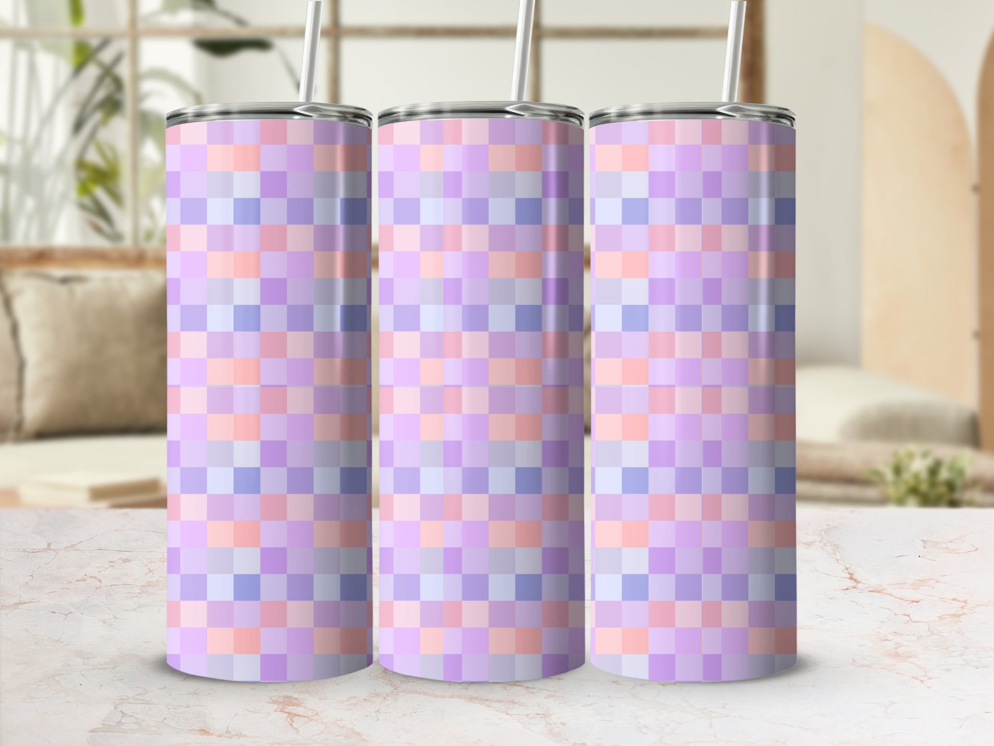 Three pastel plaid tumblers with straws on a marble surface.