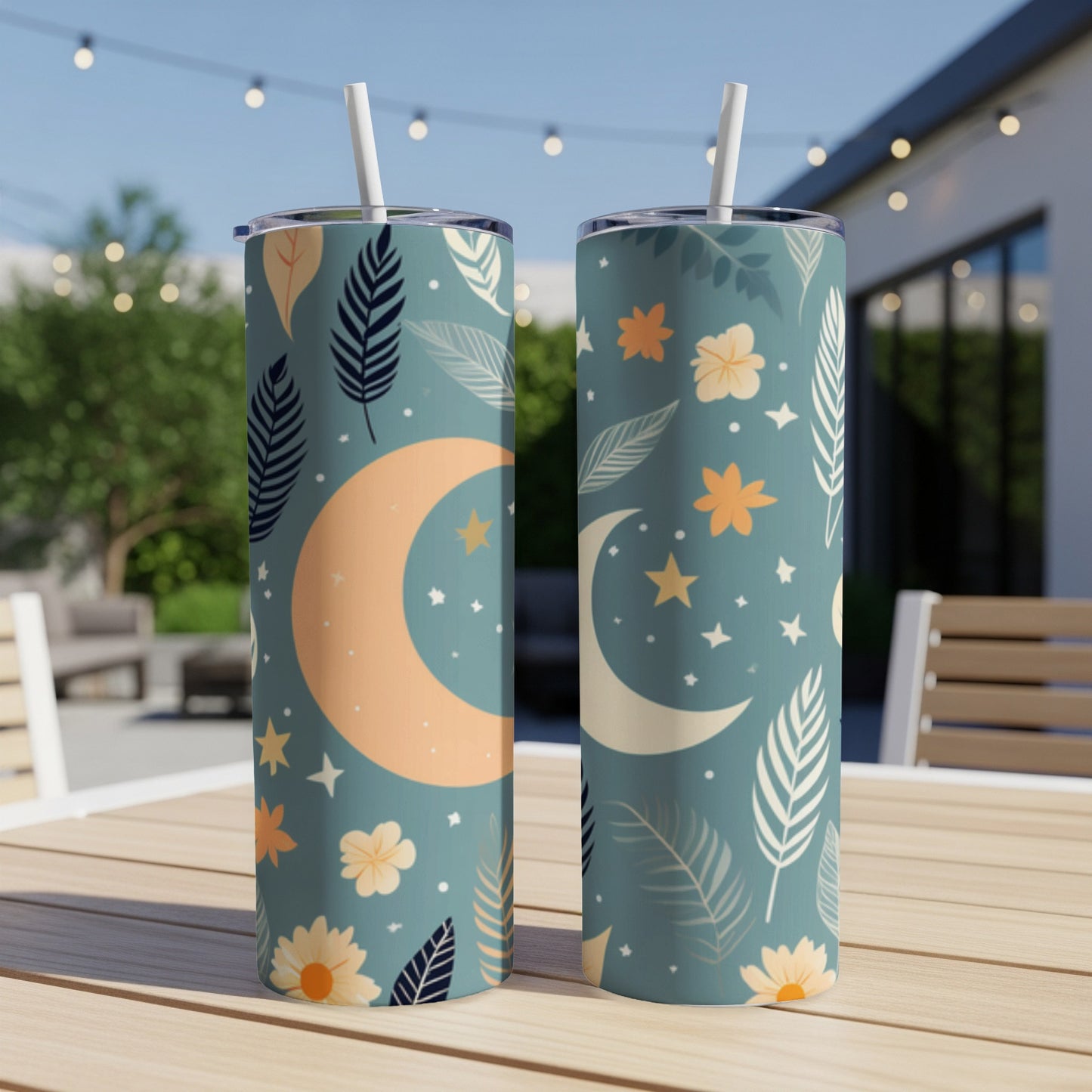 Two tall tumblers with celestial moon and floral patterns on a table.