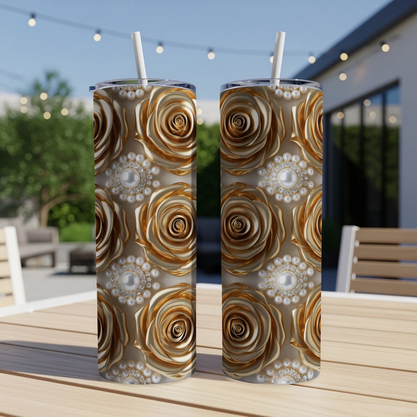 Two gold rose and pearl patterned tumblers with straws on a wooden table.