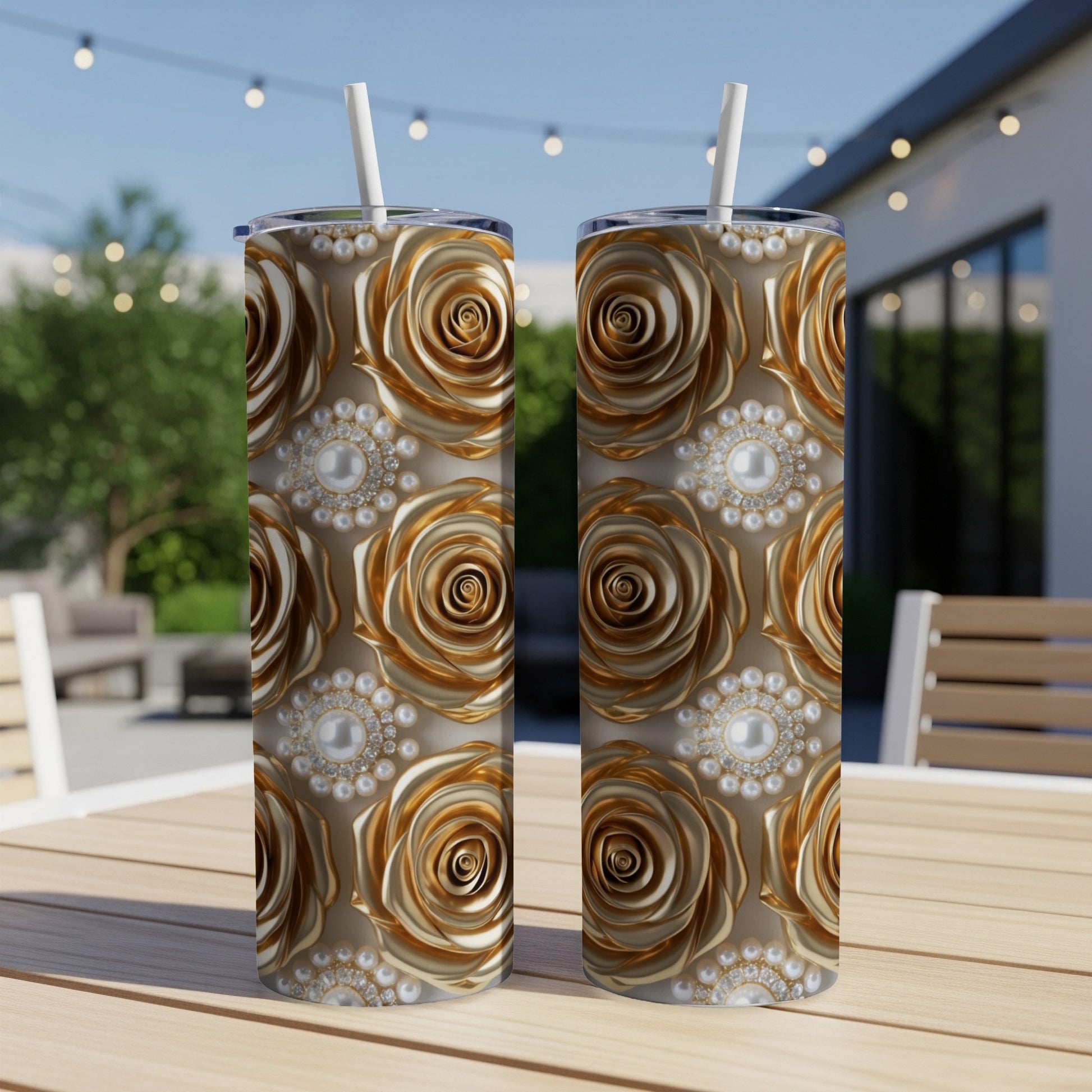 Two gold rose and pearl patterned tumblers with straws on a wooden table.