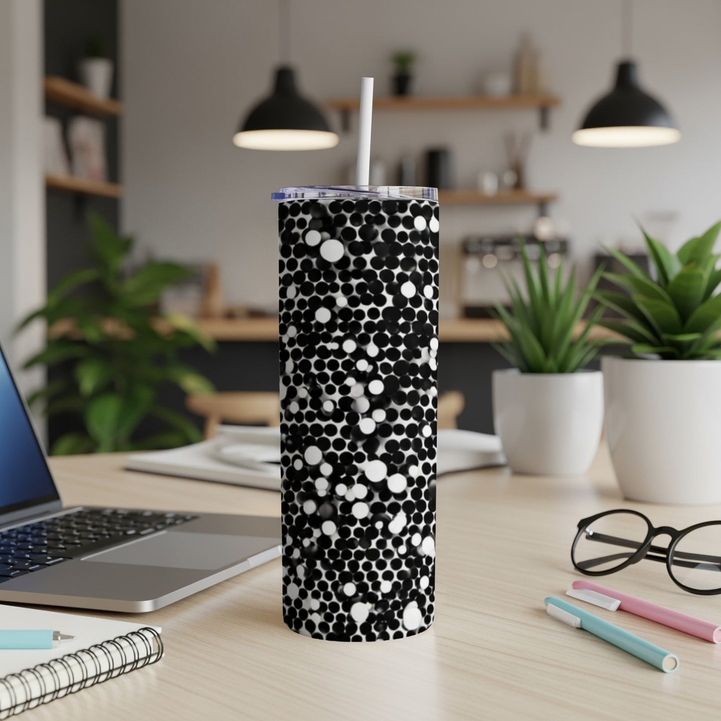 Black and white polka dot tumbler with a straw on a desk.