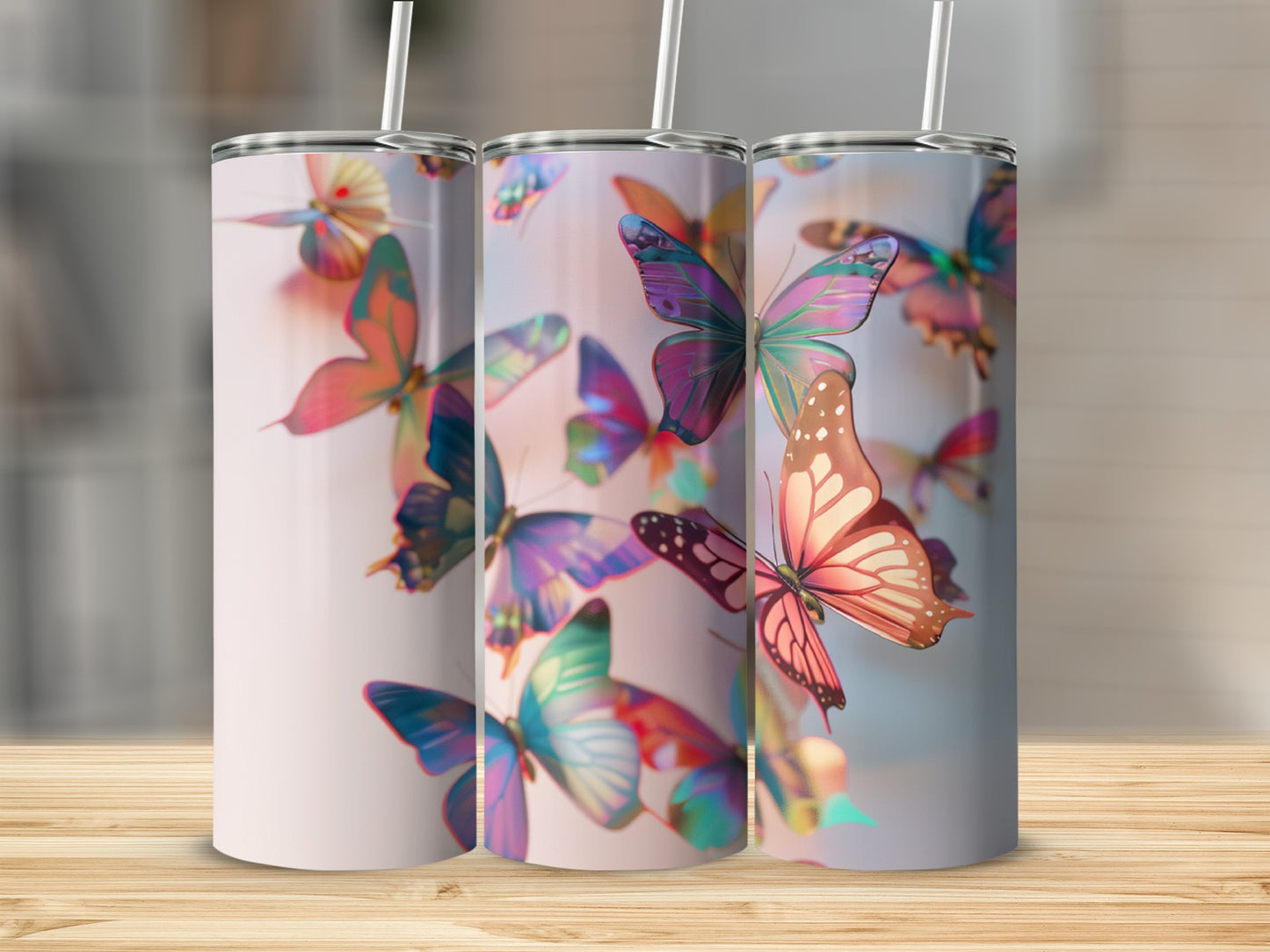 Three tumblers with colorful butterfly designs arranged on a wooden surface.