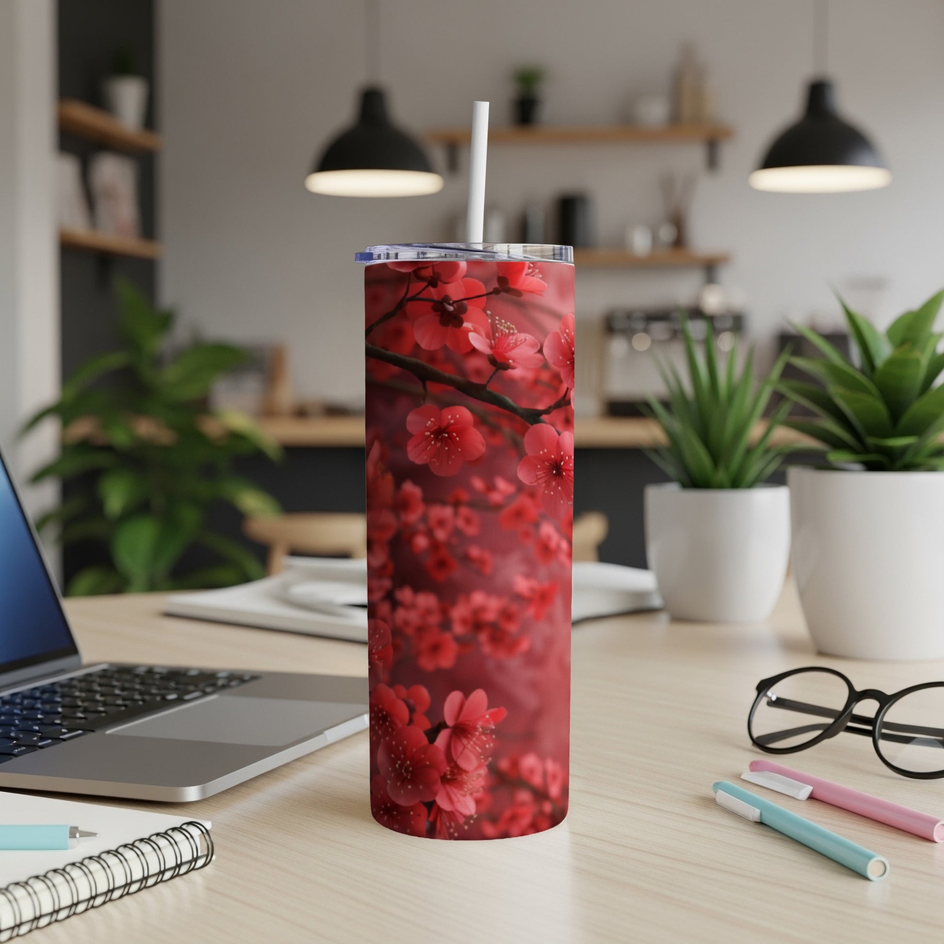 Tumbler with a close-up of red cherry blossoms on a wooden desk.