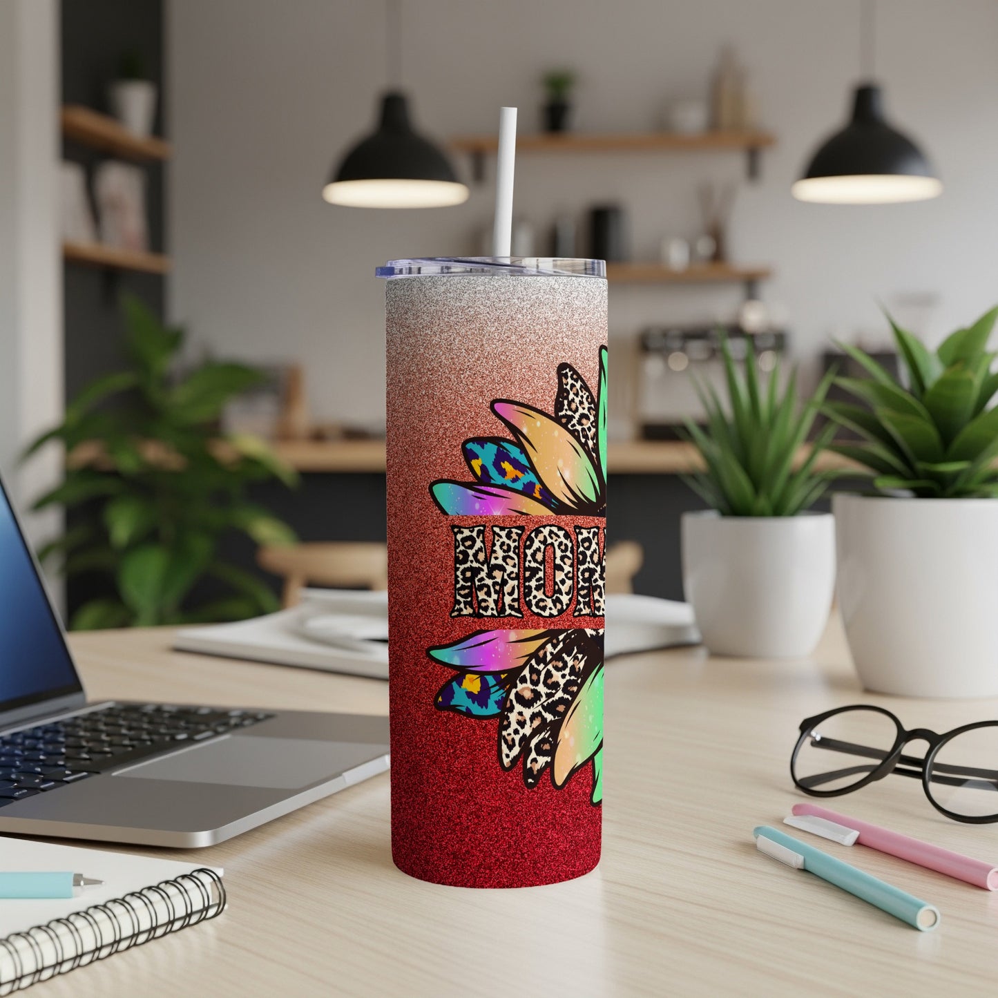 Glittery tumbler with "Mom" and sunflower design on a desk.