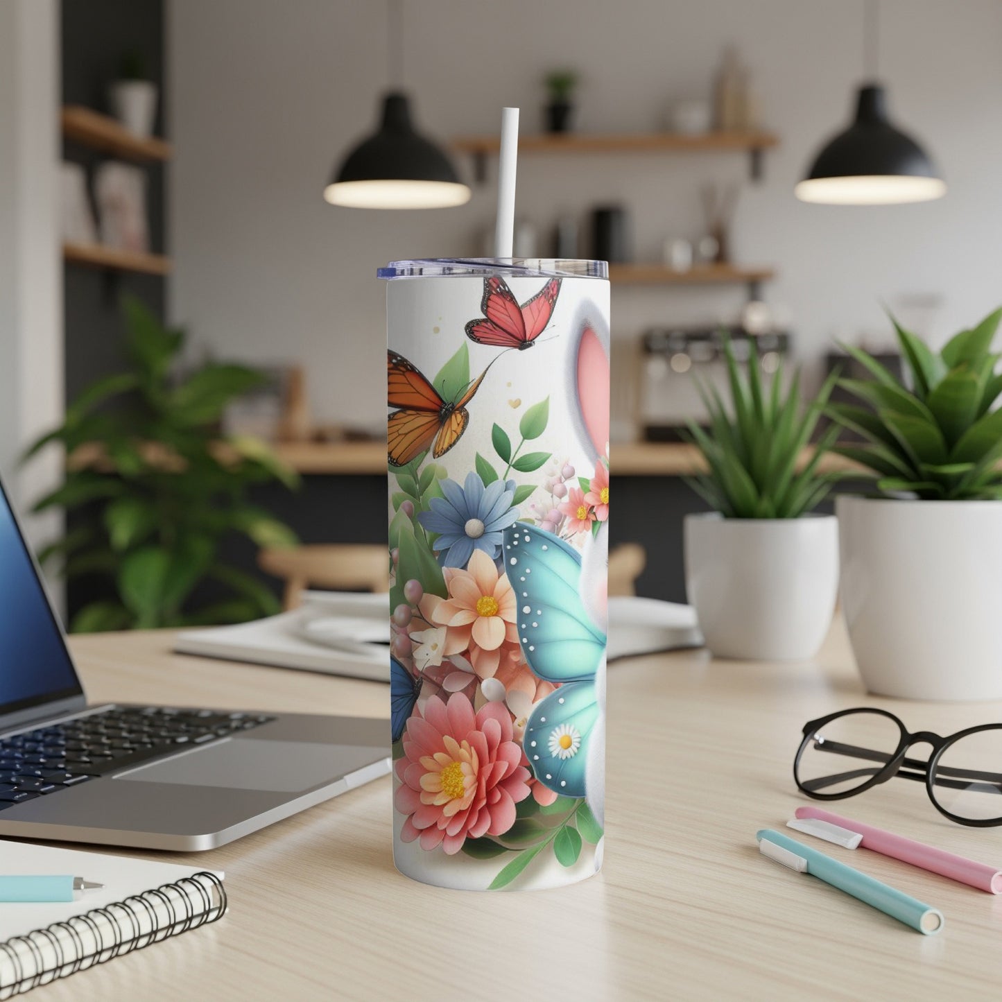White tumbler with floral and butterfly design, on a desk.