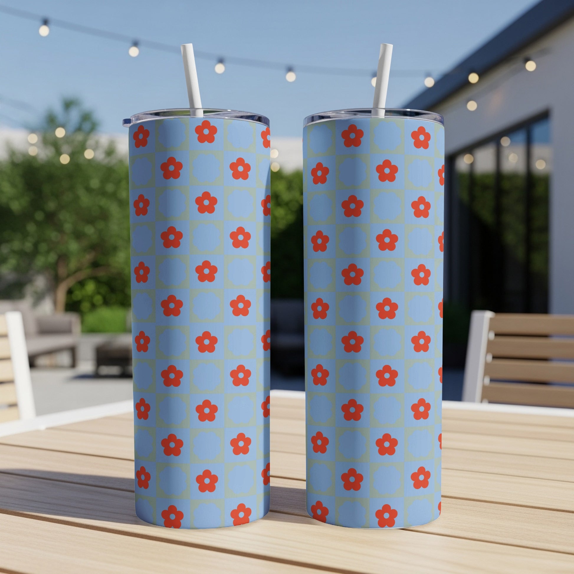Two blue tumblers with red floral pattern on a table.
