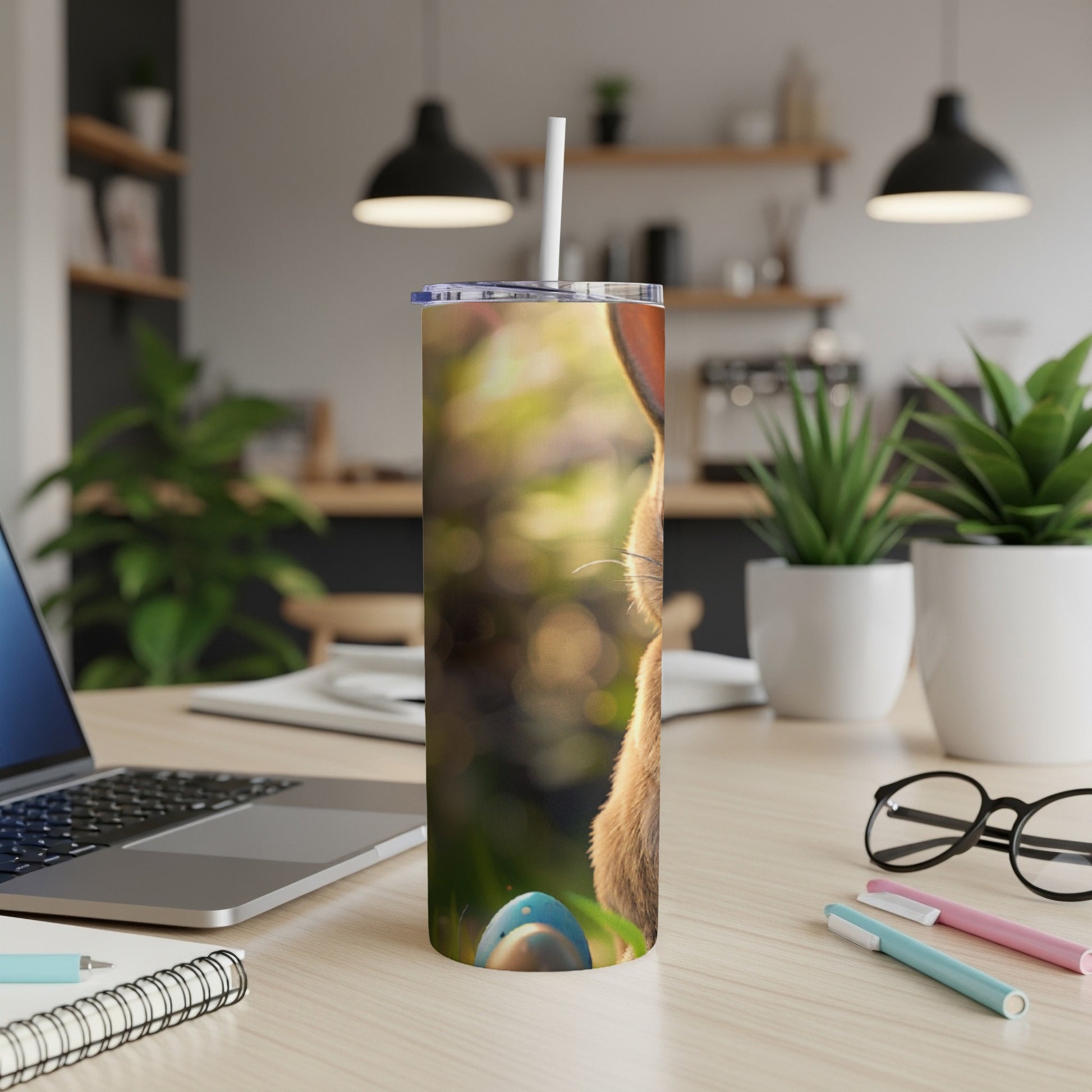 Brown bunny on a tumbler with a straw, on a desk.