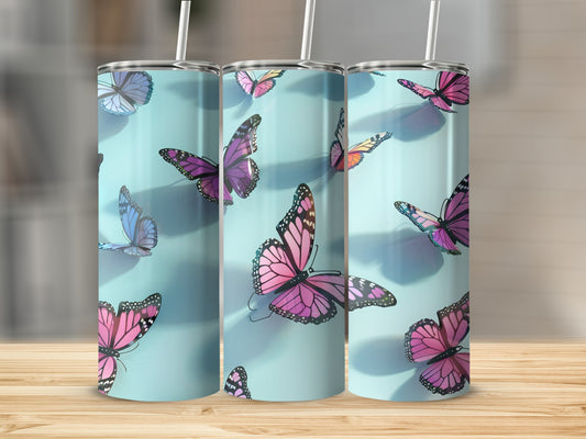 Three tumblers with colorful butterfly designs on a wooden surface.