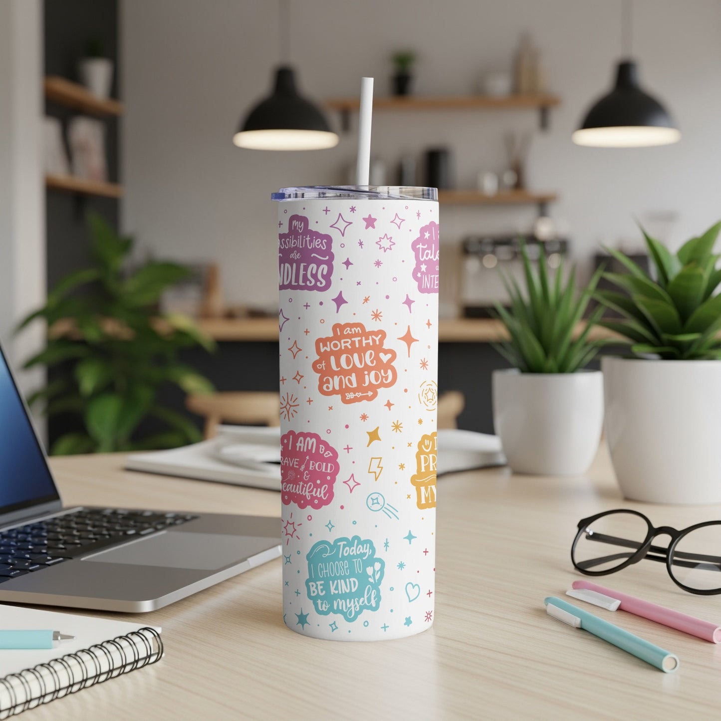 White tumbler with colorful motivational text and icons on a desk.