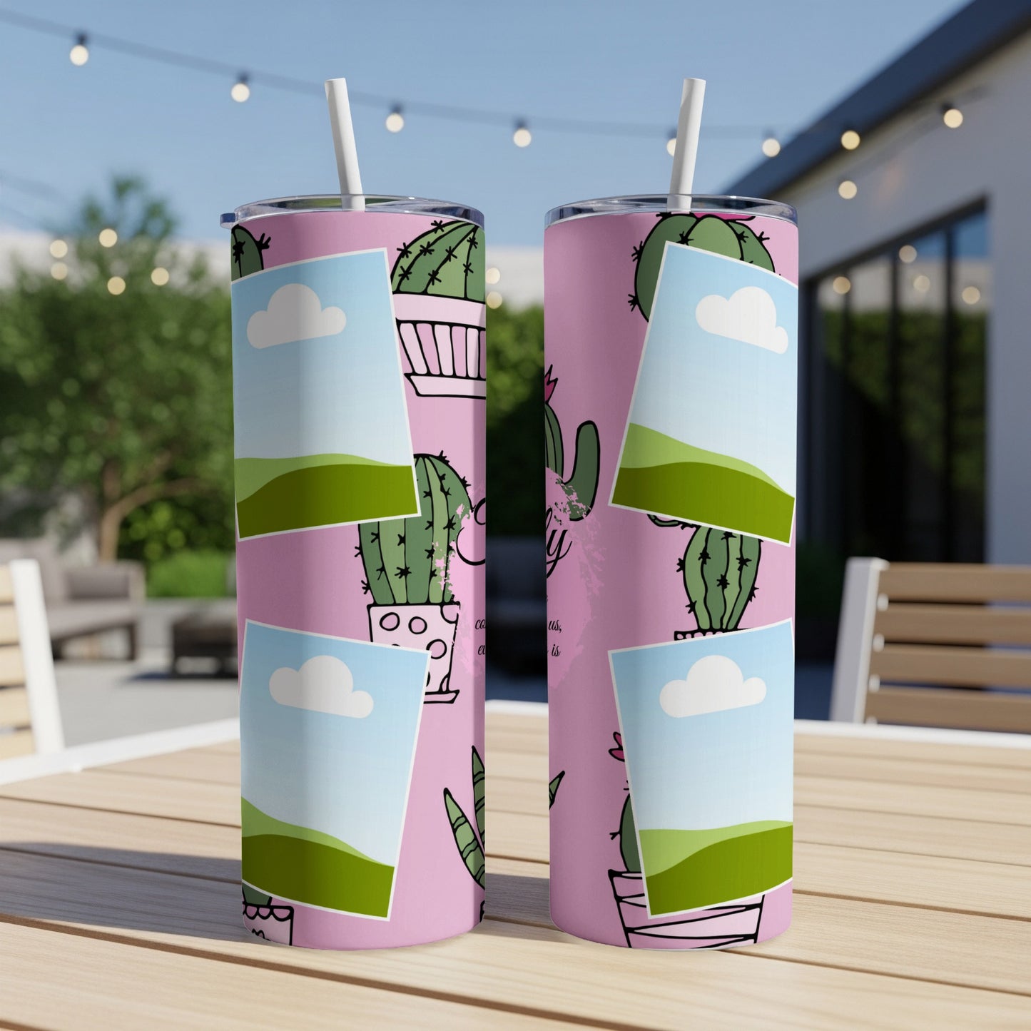 Pink tumbler with cactus pattern and framed nature scenes, set on a table.