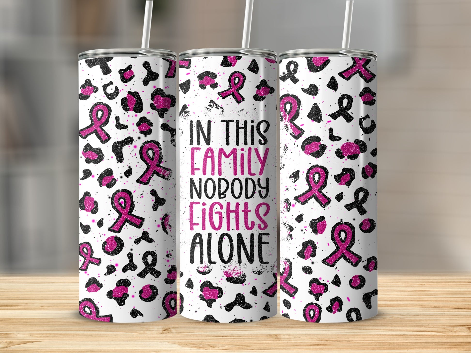 White tumbler with pink ribbon pattern and text "In this family nobody fights alone".