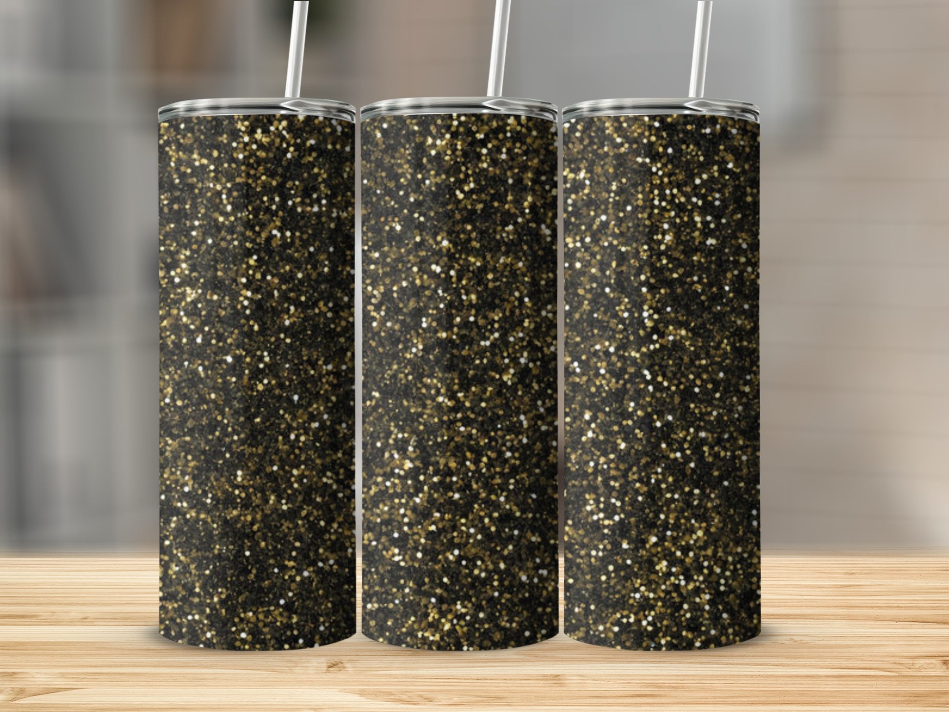 Three glitter tumblers with gold and black sparkle on a wooden surface.