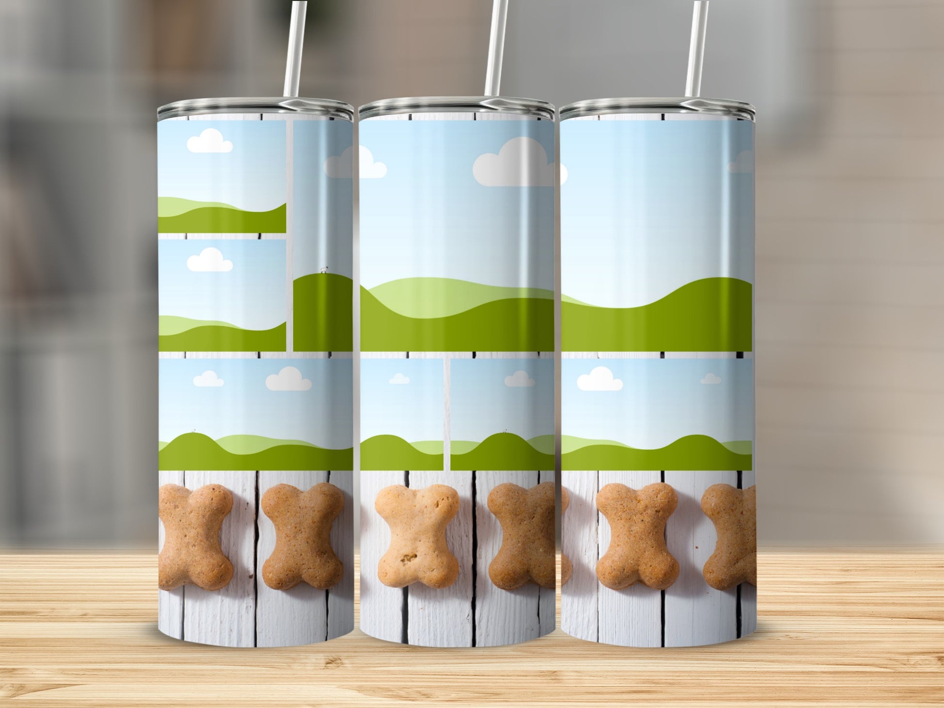 Three tumblers with bone-shaped cookies and cartoon landscape designs.