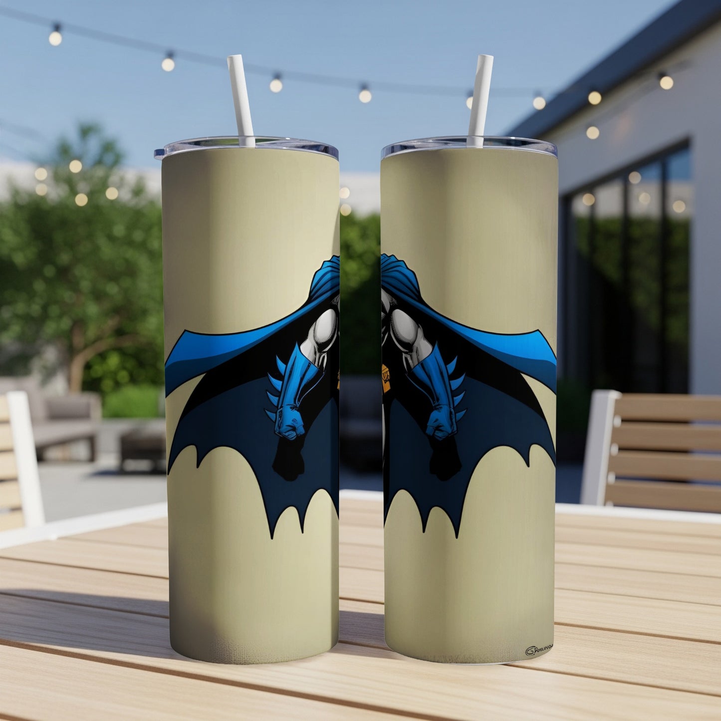 Two tan tumblers with Batman graphics, outdoors on a table.