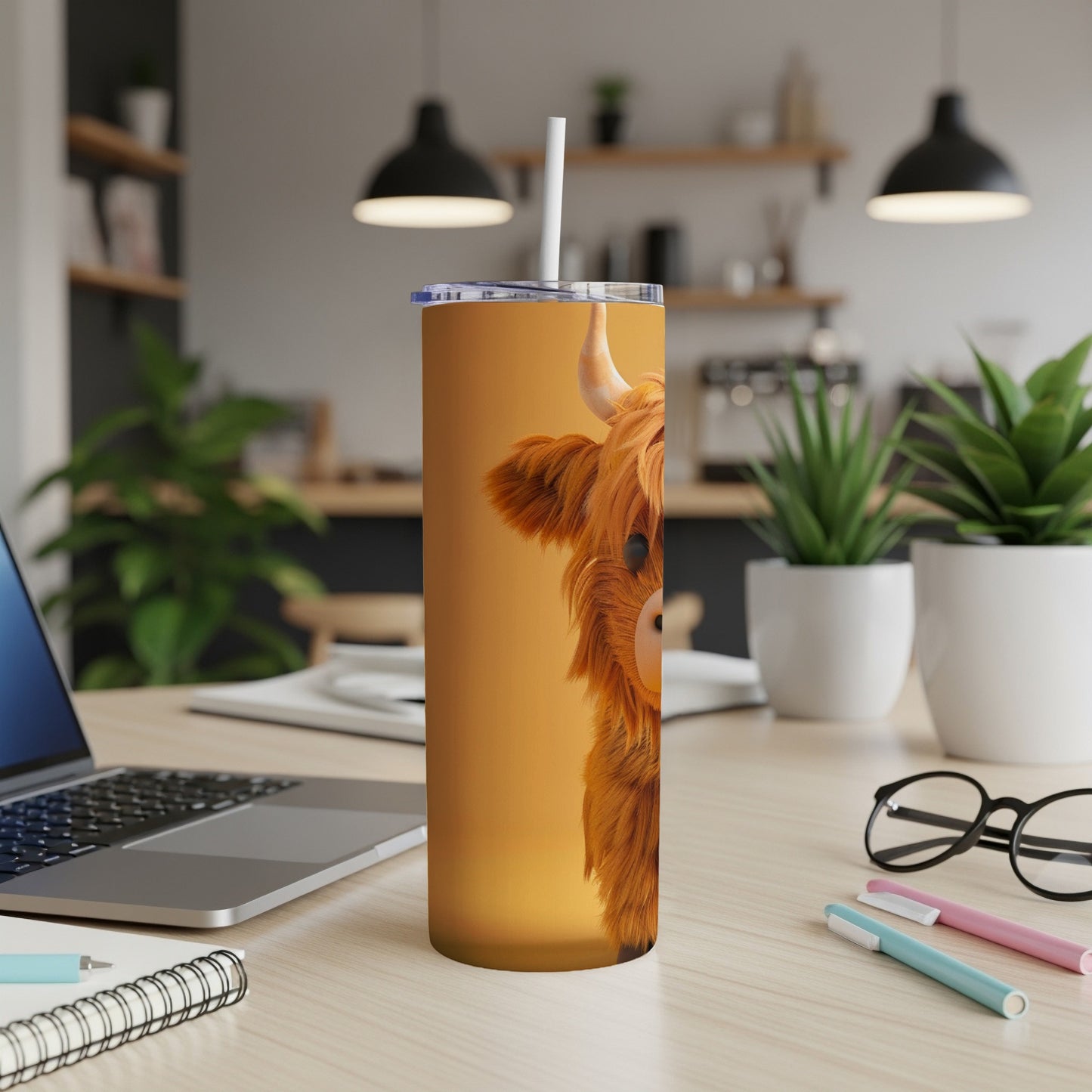 Highland cow on orange tumbler with lid and straw on desk.