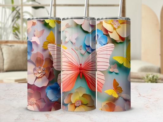 Three floral and butterfly patterned tumblers with straws on a marbled surface.