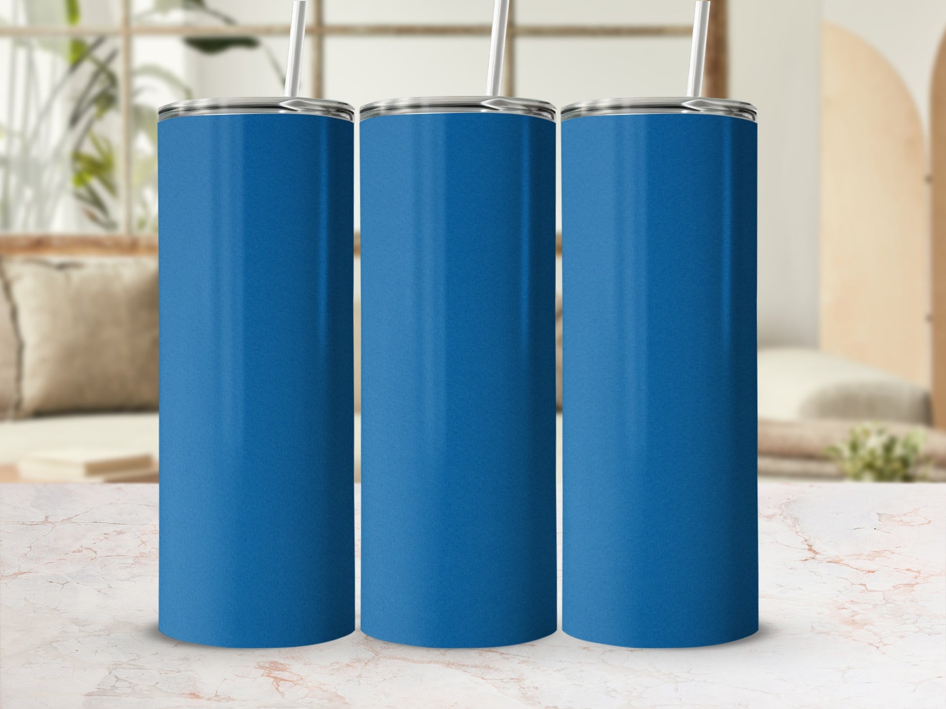 Three blue tumblers with straws on a marble surface.