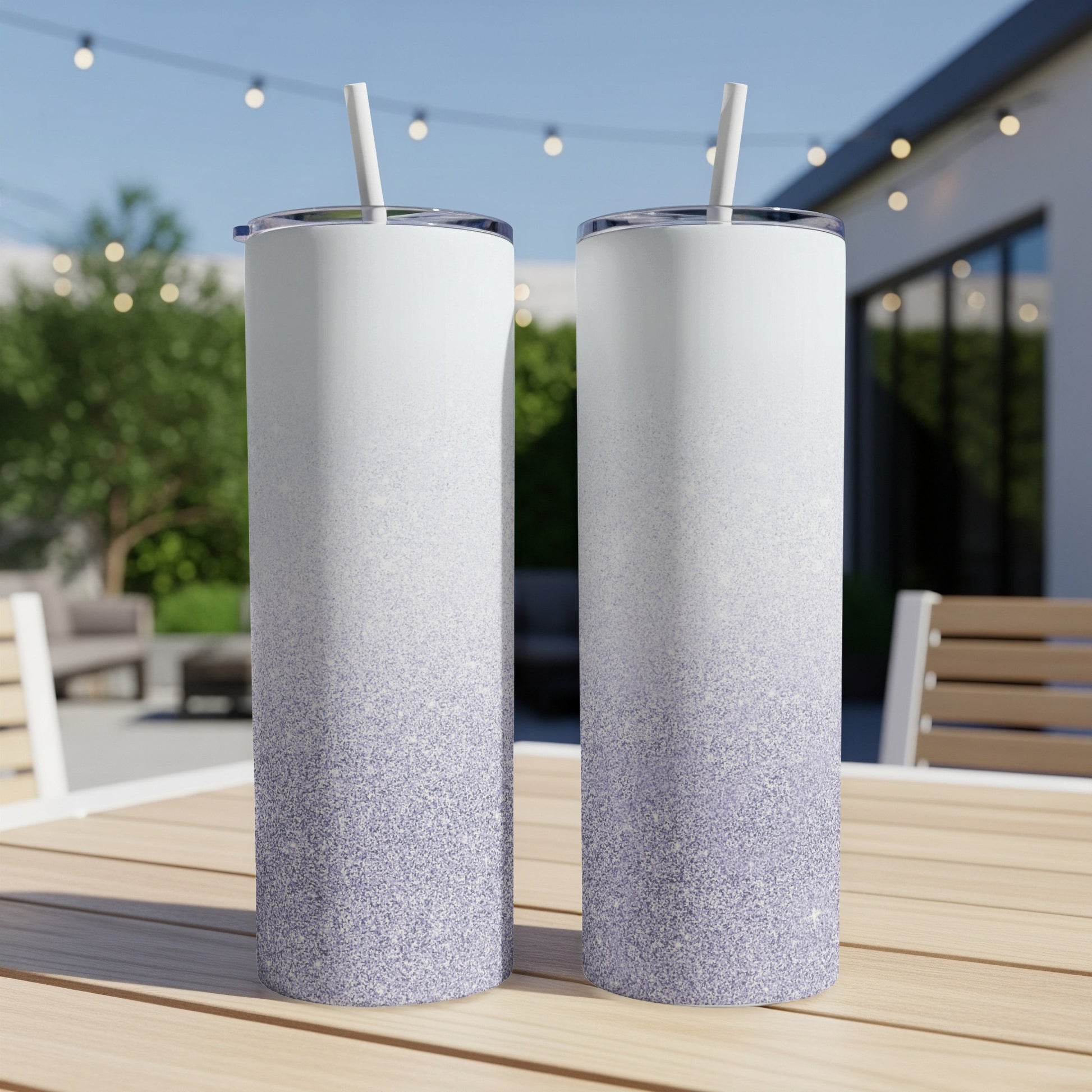 Two white and purple glitter ombre tumblers with straws on a wooden table.