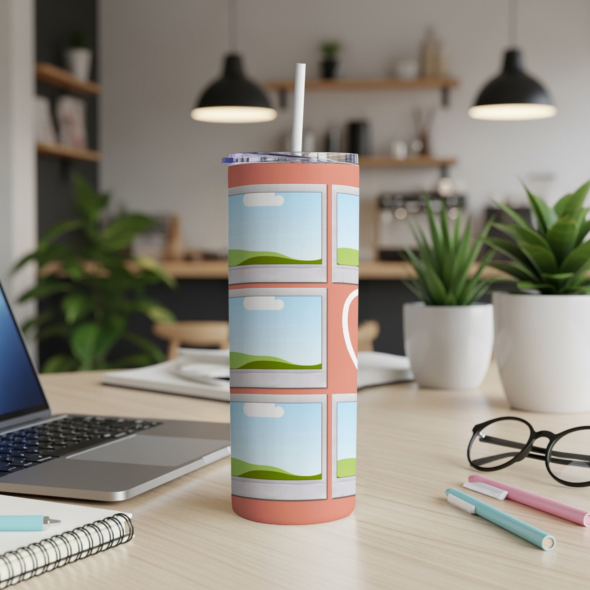 Coral tumbler with photo frame design and straw on a desk.