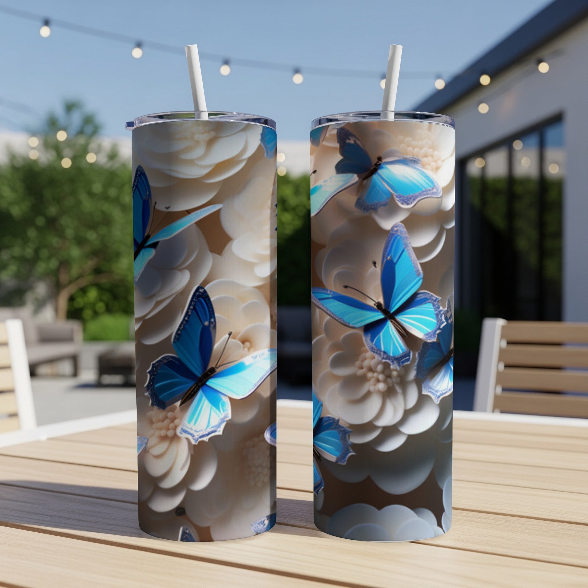Two tumblers with blue butterflies and white flowers on a table.