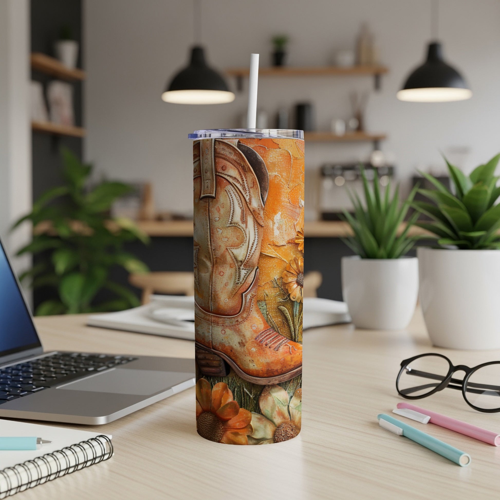 Orange cowboy boot tumbler with sunflowers on a desk.